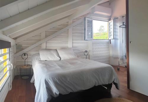 a white bed in a room with a window at Le Palma Christi in Le Carbet