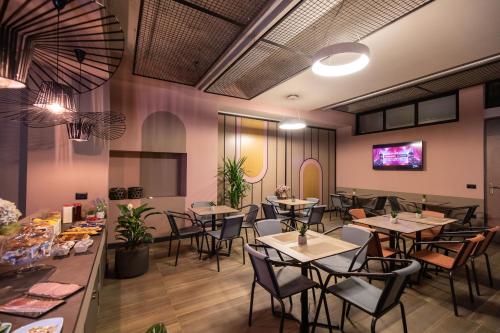 a restaurant with tables and chairs and a tv at Allure Boutique Hotel in Tirana