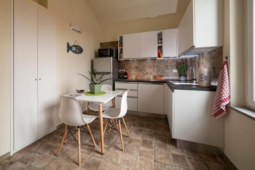 a small kitchen with white cabinets and a table and chairs at Sui Tetti, Caressa de mä in Bordighera