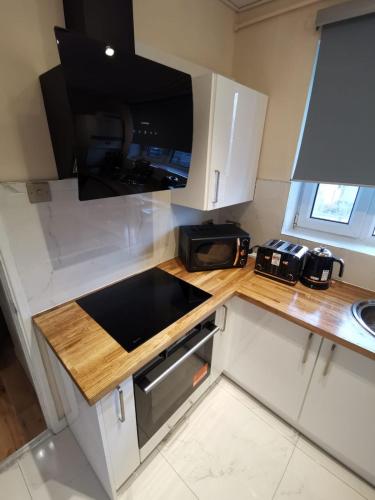 a small kitchen with a stove and a microwave at Umbrella Properties London Woolwich in London