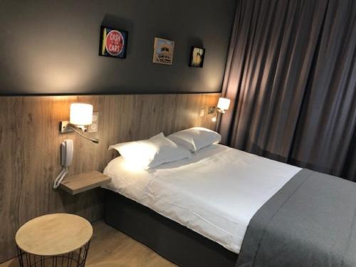 a bedroom with a bed and a table and a phone at Hotel Victor Hugo in Toulouse
