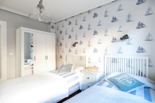 sypialnia z 2 łóżkami i ścianą z żaglówkami w obiekcie Villa La Ballena de Sonabia w mieście Oriñón