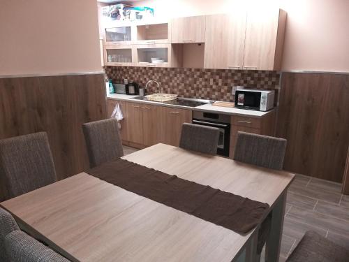 cocina con mesa de madera con sillas y barra en M7 Galéria Panzió, en Letenye