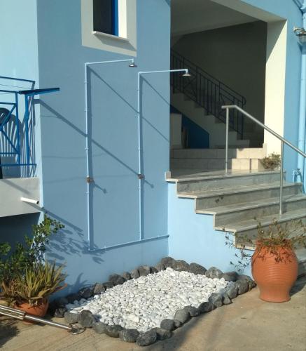 a blue building with a pile of rocks and stairs at Armenaki Apartments in Sampatiki