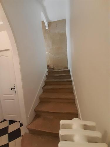 a hallway with a staircase with white walls and wooden floors at La maison d'à côté in May-sur-Orne