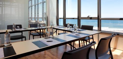a restaurant with long tables and chairs and windows at Hotel Príncipe de Asturias in Gijón
