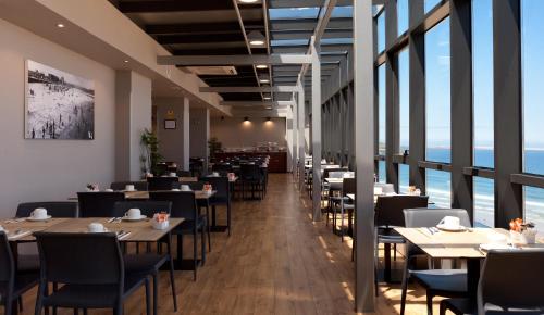 a restaurant with tables and chairs and large windows at Hotel Príncipe de Asturias in Gijón