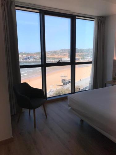 a bedroom with a bed and a view of a beach at Hotel Príncipe de Asturias in Gijón