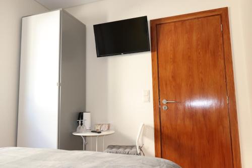1 dormitorio con puerta de madera y TV en la pared en Arouca Guest House, en Arouca