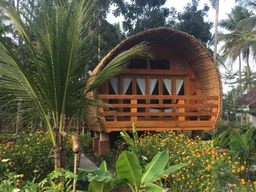 a small hut in a garden with flowers and trees at Lagoona Beach Bungalows - Eco Bungalows Batukaras in Batukaras