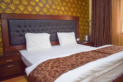 Schlafzimmer mit einem großen Bett mit einem Kopfteil aus Holz in der Unterkunft Hotel Prestige in Aqaba