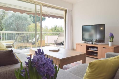 un salon avec un canapé et une télévision dans l'établissement 2-Br Apartment with pool & garage - 10 min walk to center, à Cannes