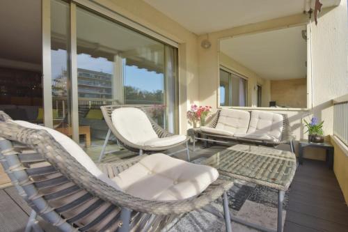 - une terrasse couverte avec des chaises blanches, des tables et des fenêtres dans l'établissement 2-Br Apartment with pool & garage - 10 min walk to center, à Cannes