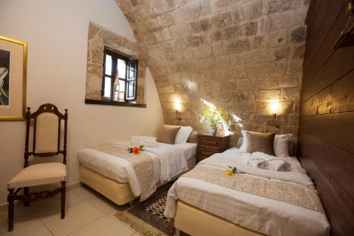 a bedroom with two beds and a stone wall at Medieval Dreams Villa in Rhodes Town