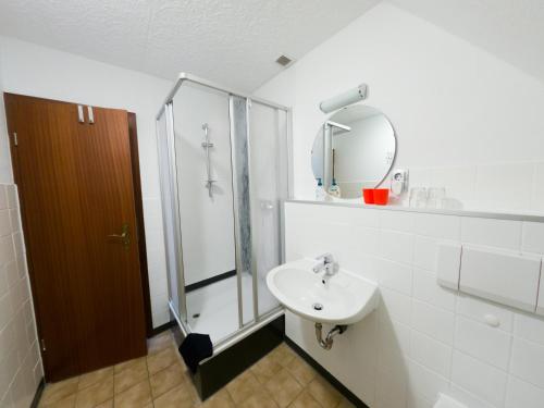 a bathroom with a sink and a shower and a mirror at Pension Dalina in Sagard