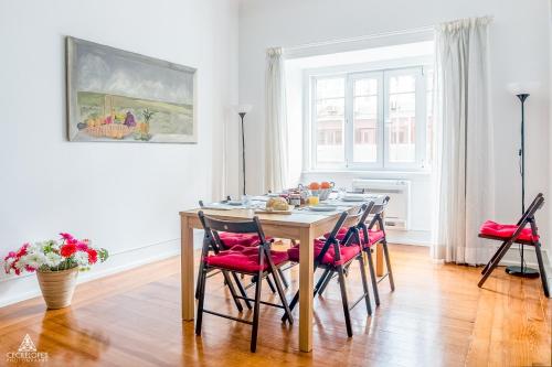 a dining room with a table with red chairs at Casa da Avenida Lisboa in Lisbon