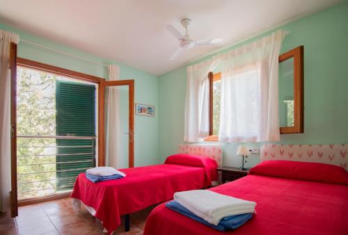 two red beds in a room with a window at Camí de la Victòria in Alcudia