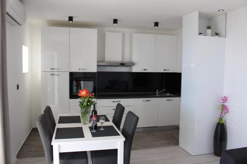 a kitchen with white cabinets and a table with flowers on it at Holiday Apartment Lira jacuzzi - sea view- terrace in Mlini
