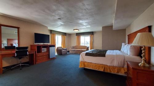 a hotel room with a bed and a desk and a television at Ramada by Wyndham Flagstaff East in Flagstaff