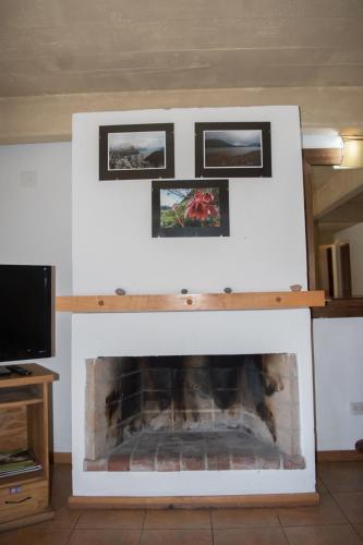 a fireplace with three pictures on top of it at Cabañas Rucaleufu in San Martín de los Andes