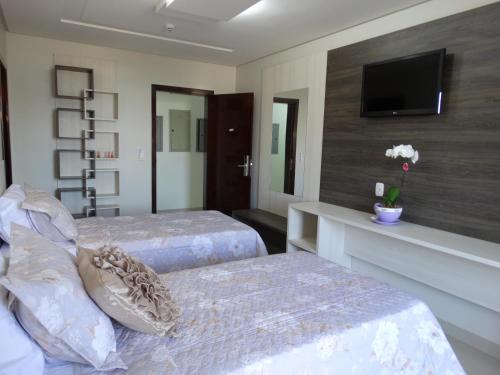 a bedroom with two beds and a tv on a wall at Tezla Hotel in Primavera do Leste
