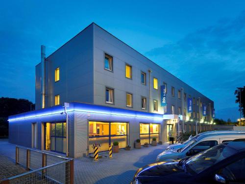 a building with cars parked in a parking lot at ibis budget Aachen Raeren Grenze in Raeren