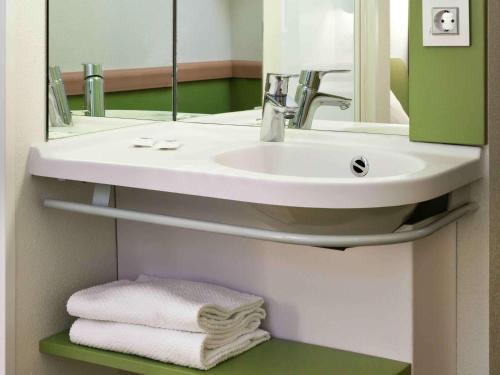 y baño con lavabo, espejo y toallas. en Ibis Budget Málaga Centro, en Málaga