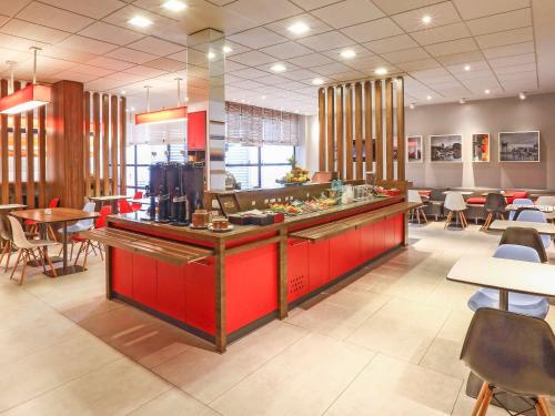 a restaurant with a red counter and tables and chairs at ibis Buenos Aires Obelisco in Buenos Aires