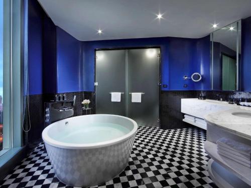 a bathroom with a large tub and blue walls at SO/ Bangkok in Bangkok