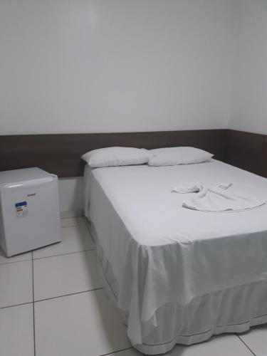 uma cama com lençóis brancos e almofadas num quarto em Pousada Pampa Gaúcho em Teresina