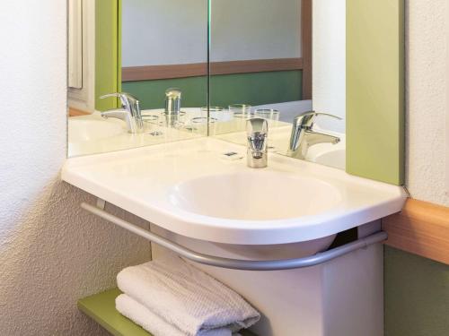 bagno con lavandino bianco e specchio di Ibis Budget St Gratien - Enghien-Les-Bains a Saint-Gratien