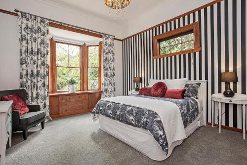 a bedroom with a bed and a chair and a window at Pepper Tree Villa in Masterton