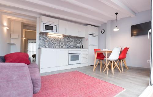 タラゴナにあるPlaça Forum - Aerisのキッチン(白いキャビネット、テーブル、赤い椅子付)