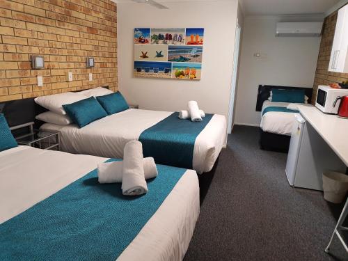 Habitación de hotel con 3 camas y microondas en Beerwah Motor Lodge en Beerwah