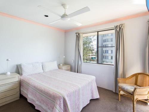 a bedroom with a bed and a window and a chair at Oxley 8 at Tuncurry in Tuncurry