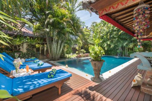 a poolside deck with blue chairs and a swimming pool at Villa Kaja by Nagisa Bali in Seminyak