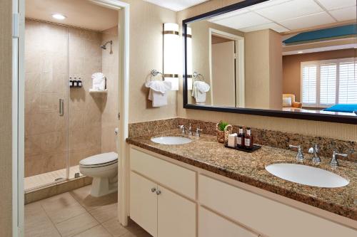 a bathroom with two sinks and a toilet and a mirror at Empress Hotel La Jolla in San Diego