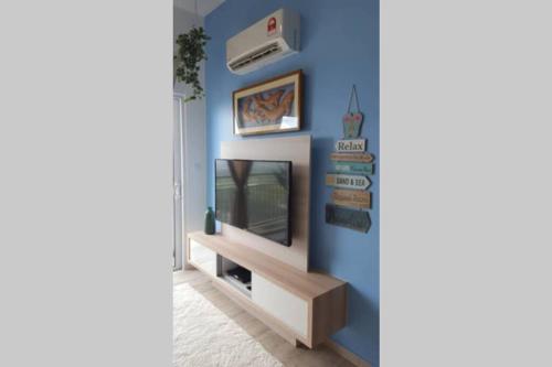 a living room with a tv and a blue wall at Mesa Hill Nilai - Welcome to the Nautica in Nilai