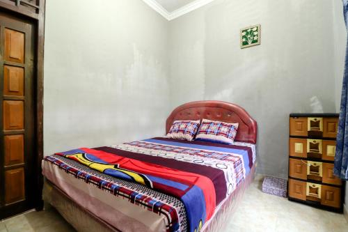 a bedroom with a bed with a red head board at Jemakir Homestay in Sermo