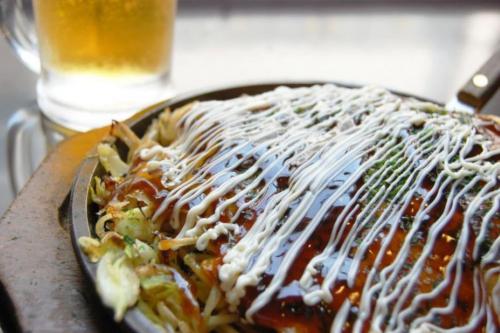 a pizza with cheese and sauce on a table with a drink at Hiroshima Town Hotel in Hiroshima