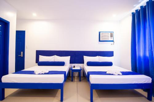 two beds in a room with blue curtains at Skytel Palawan in Puerto Princesa City