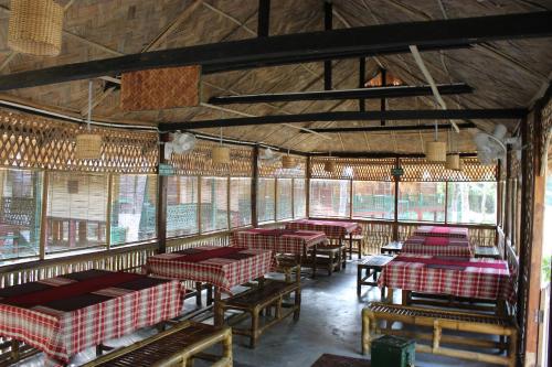 una habitación con mesas y sillas en un restaurante en Nature Hunt Eco Camp, en Kāziranga