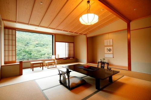 a living room with a table and a large window at Kotohira Onsen Kotosankaku in Kotohira