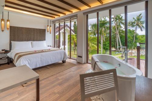 ein Schlafzimmer mit einem Bett und einer Badewanne in einem Zimmer in der Unterkunft North Zen Villas in Panglao