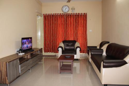 a living room with a couch and a tv at Phoenix Serviced Apartment - Sai Illam in Chennai