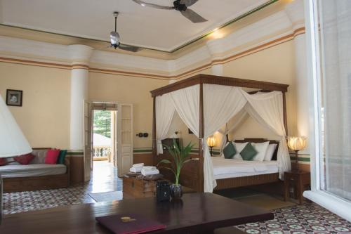 sypialnia z łóżkiem z baldachimem i stołem w obiekcie La Villa w mieście Battambang