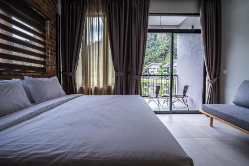 a bedroom with a bed and a chair and a balcony at Sementra Hot Spring Nature Resort in Gopeng