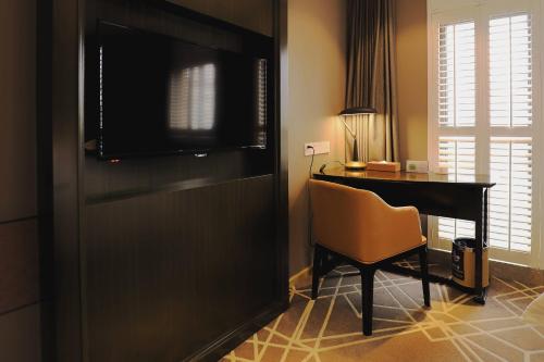 a room with a desk with a television and a chair at Jinjiang Metropolo Hotel Classic Nanjing Road (East) Shanghai in Shanghai