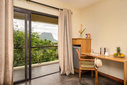 a room with a desk and a window with a view at Happy Days Guest House in Le Morne