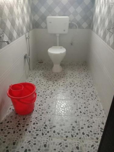 a bathroom with a toilet and a red bucket at Woodland Lodge and Restaurant in Guwahati